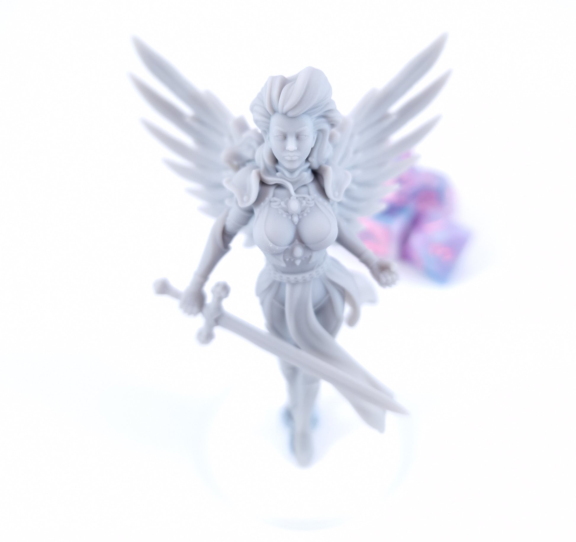 Aasimar Paladin miniature with large angelic white wings, ornate gold armor, flowing green and white tabard, red hair, and a longsword, posed on a display base.